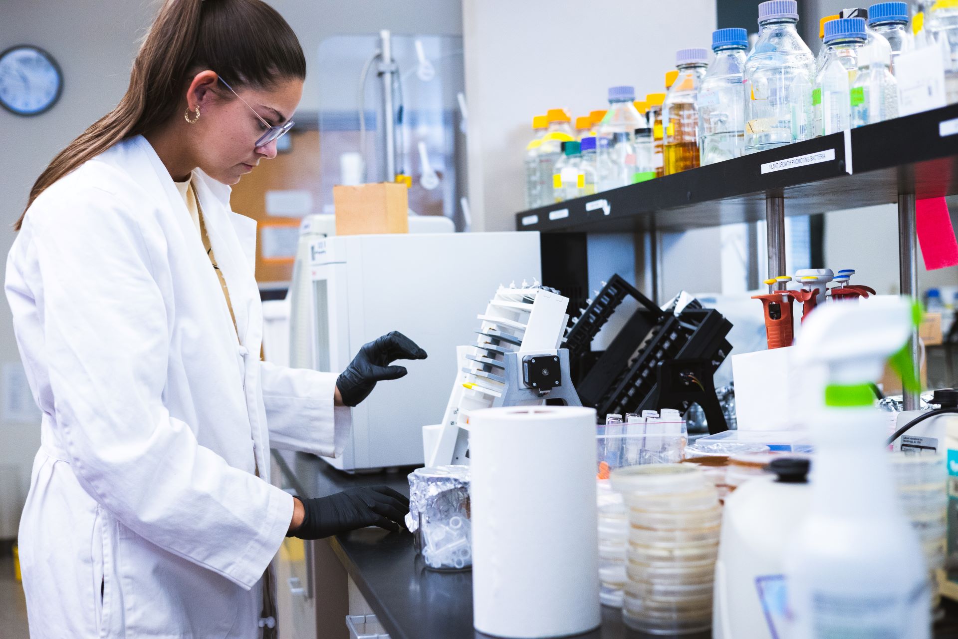 Female student performing a blood analysis next to an analysis machiney